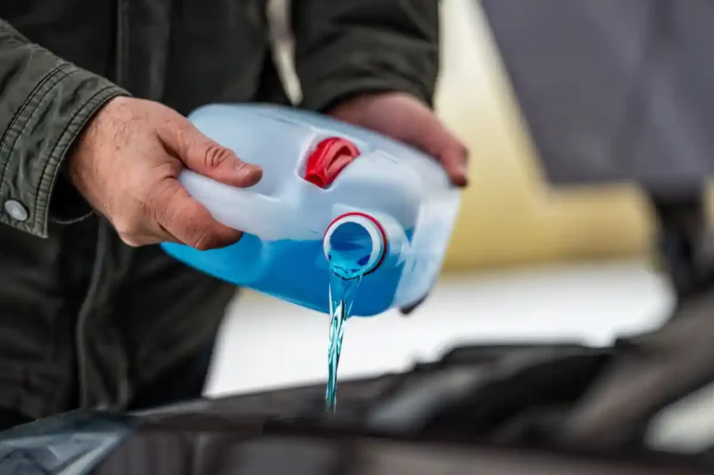 Une personne qui verse du liquide de refroidissement dans le moteur