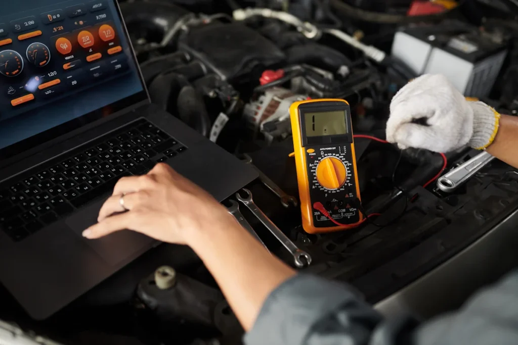 Une personne qui fait un diagnostic auto sur un ordinateur et avec un multimètre