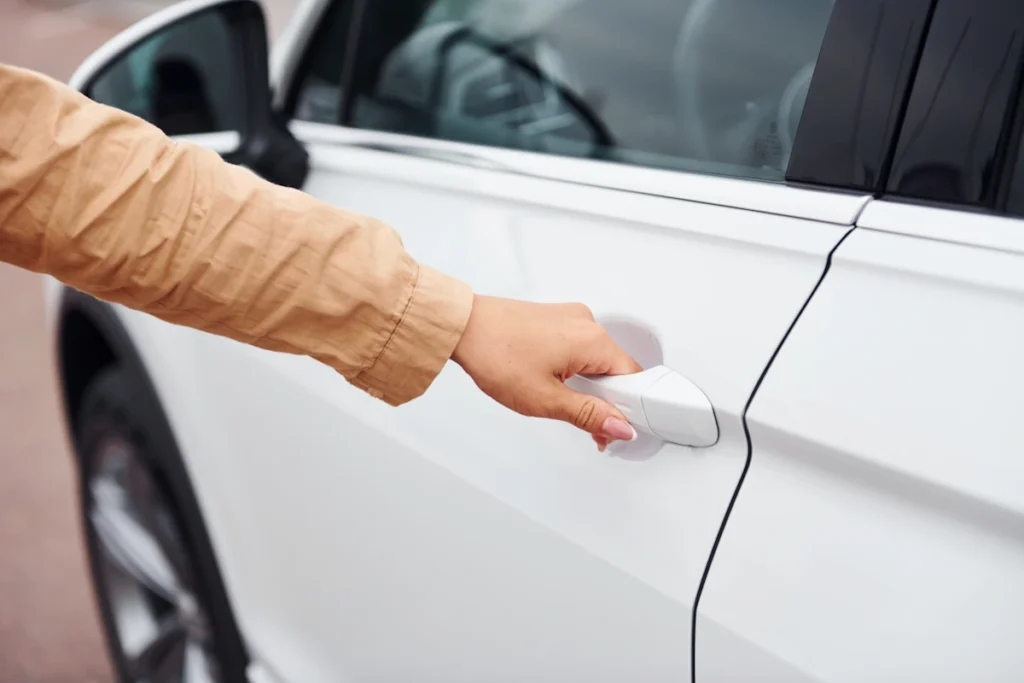 Une femme qui tient la poignée d'une porte de voiture blanche