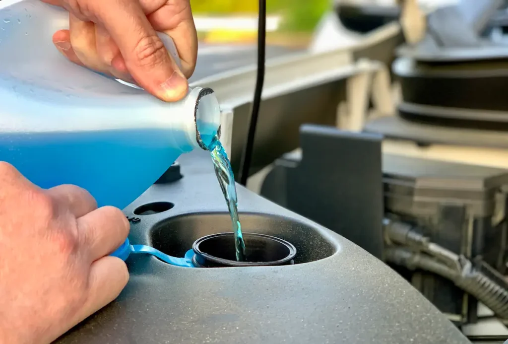 Une personne qui ajoute du liquide de refroidissement dans une voiture