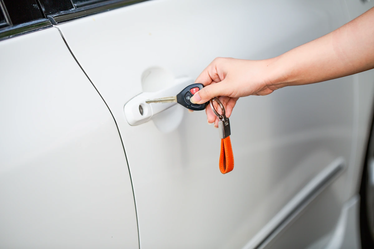 Une personne qui va introduire une clé dans la serrure d'une porte de voiture