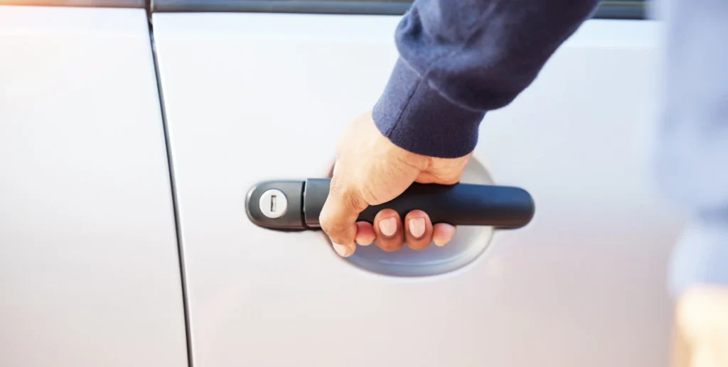 Un homme qui tient la poignée de porte d'une voiture
