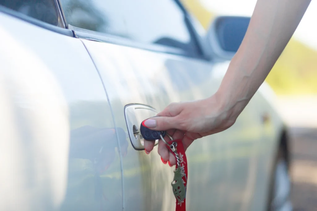 Une personne qui tient une clé sur la serrure d'une porte de voiture