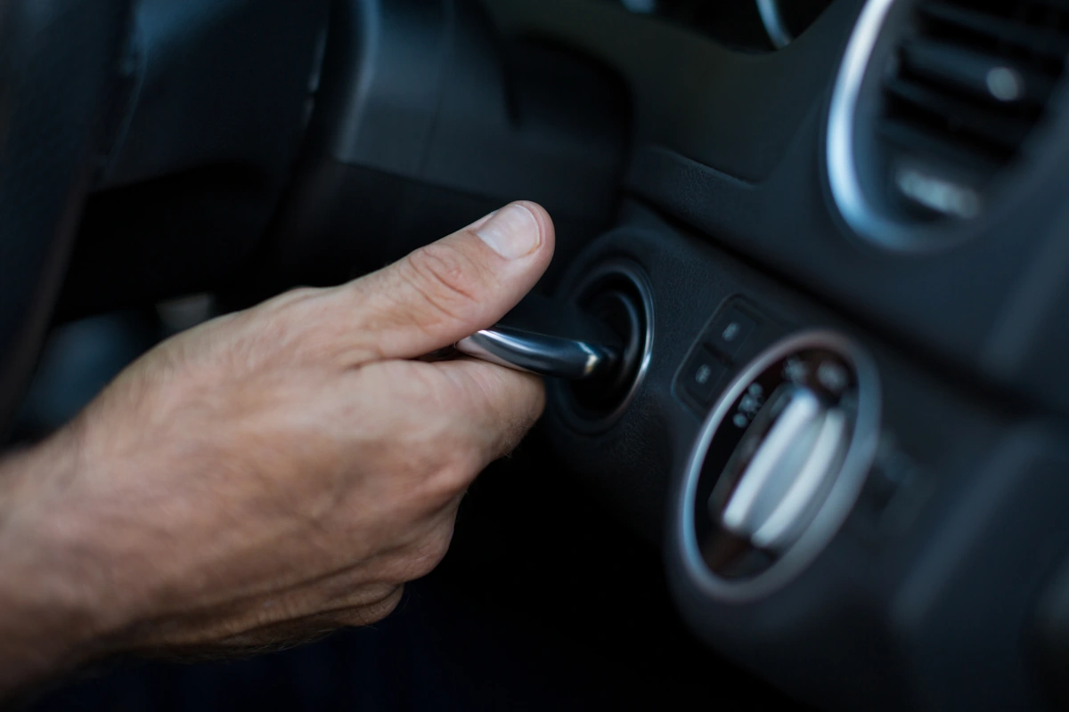 Une personne qui tourne la clé de contact d'une voiture pour actionner le démarreur
