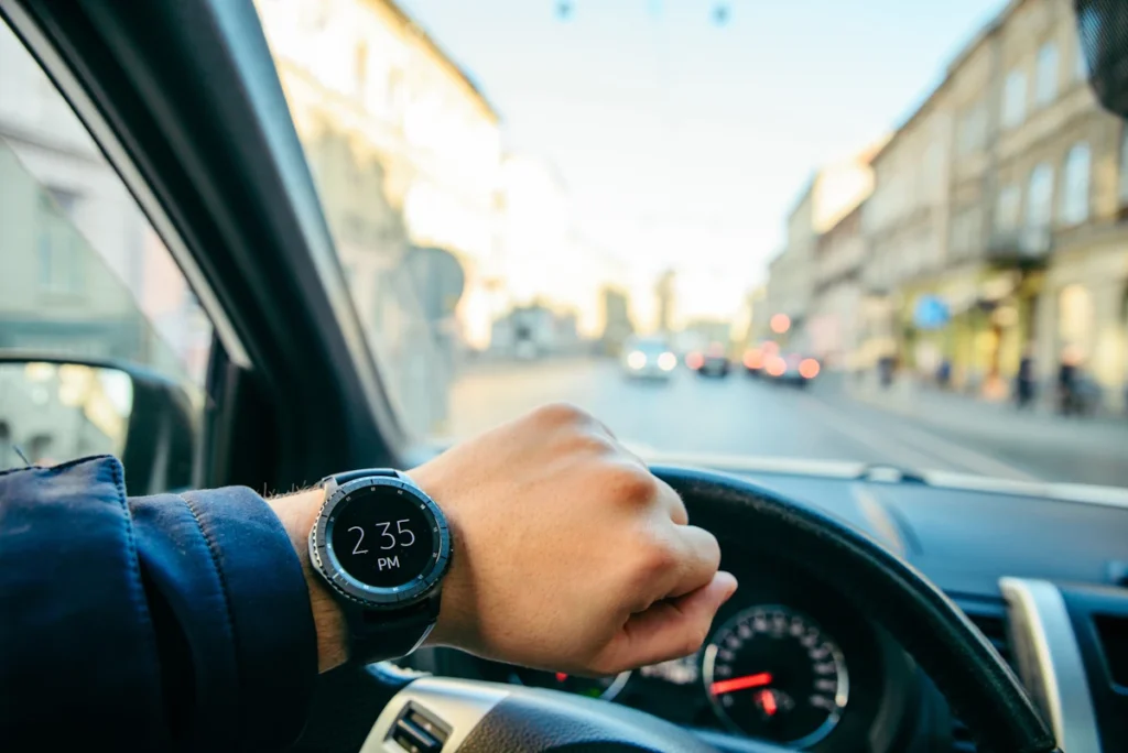 Une personne derrière un volant de voiture qui regarde sa montre